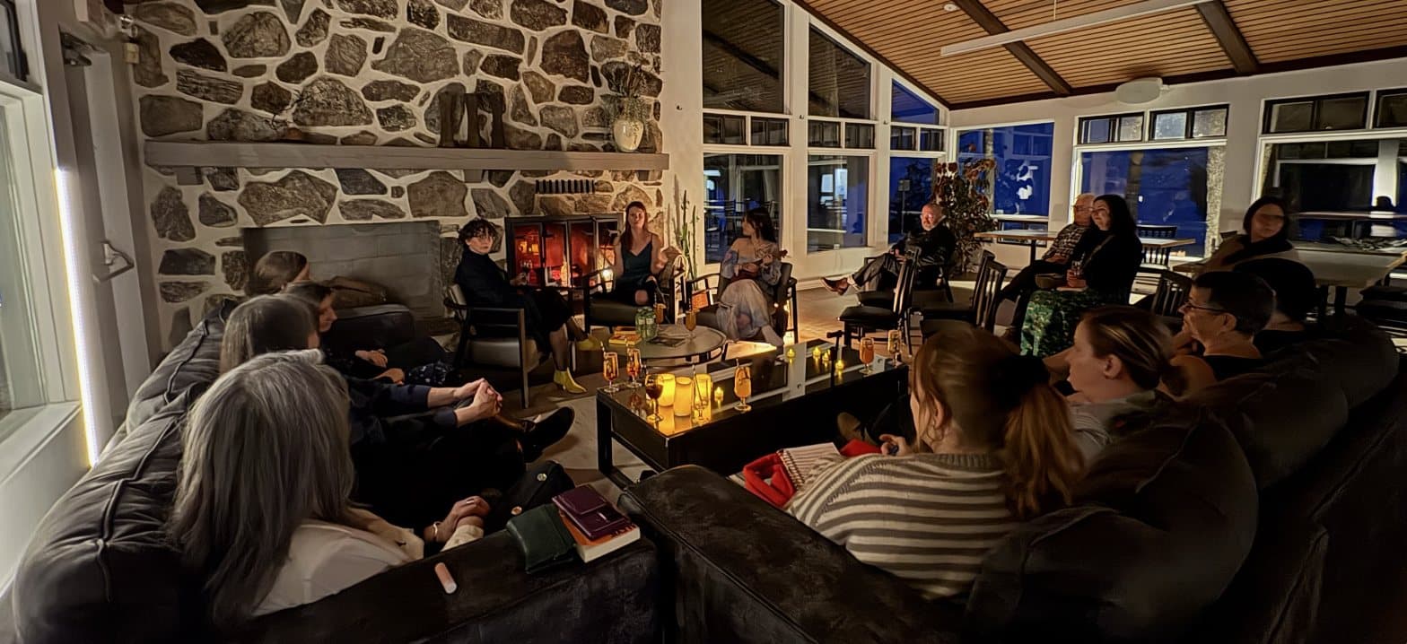 Une quinzaine de personnes réunies dans un salon, à la lueur des bougies, lors d'une séance du club de lecture.